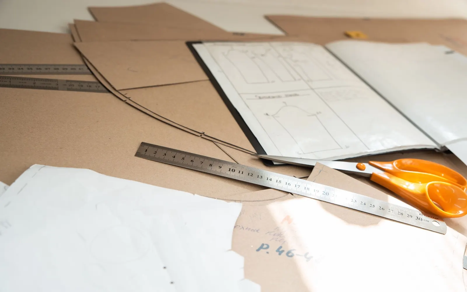 Garment patterns, measuring tools and scissors on a clothing development workspace