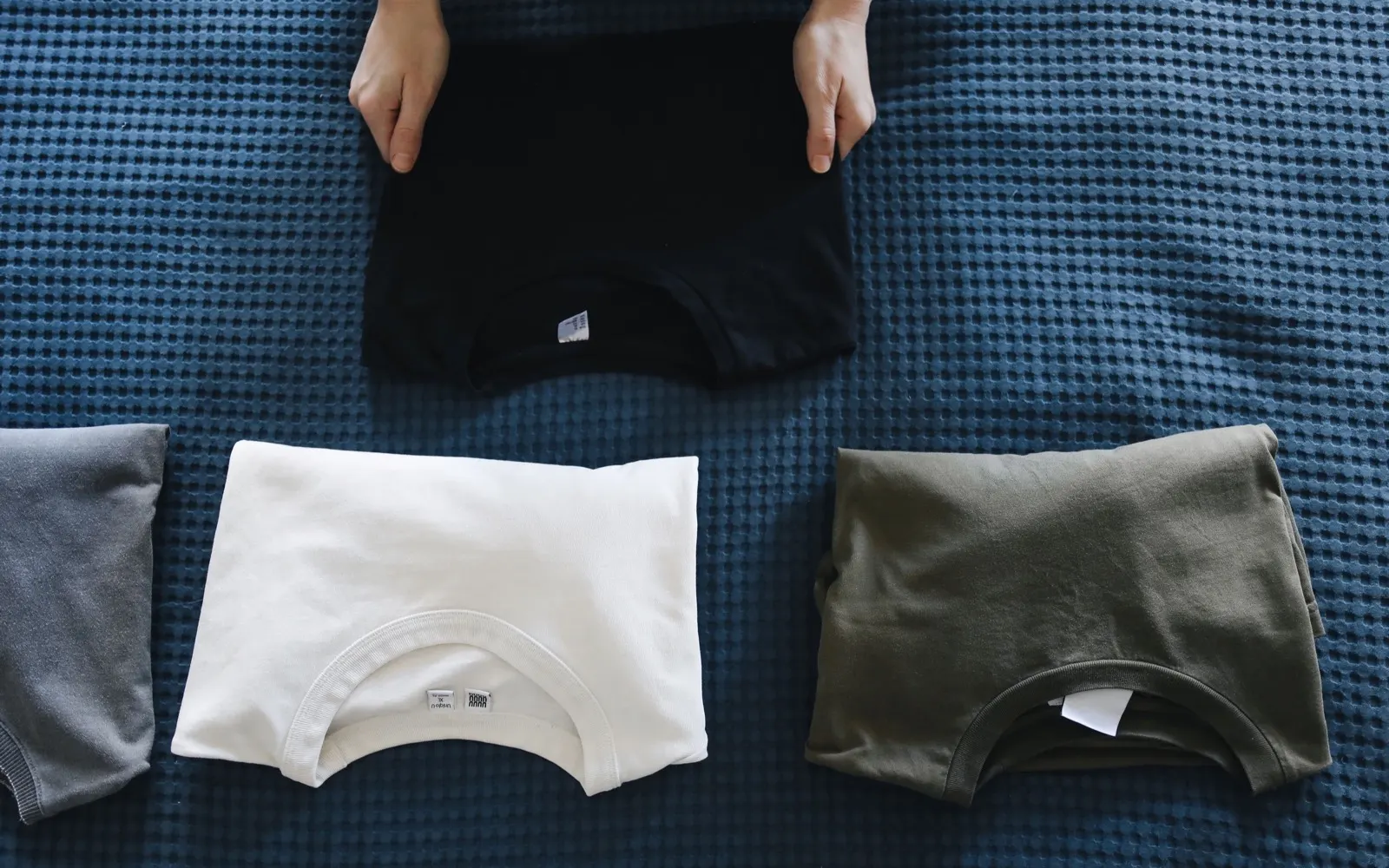 Folded unbranded T-shirts arranged for comparing everyday garment choices